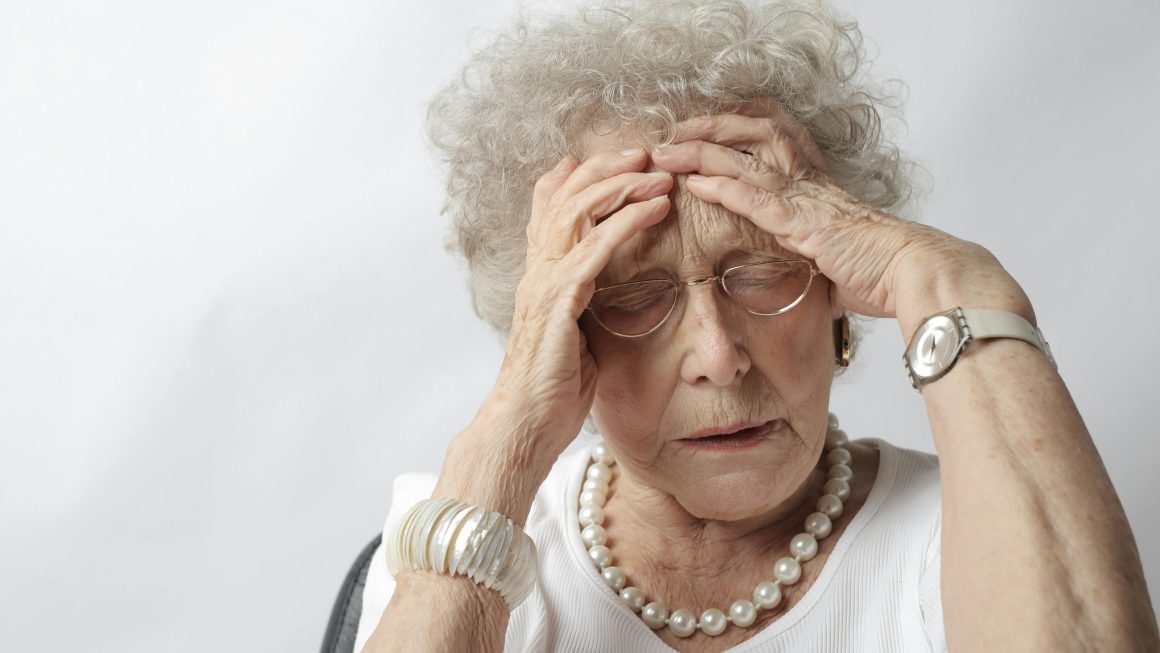 older woman in pain, with both hands on her head