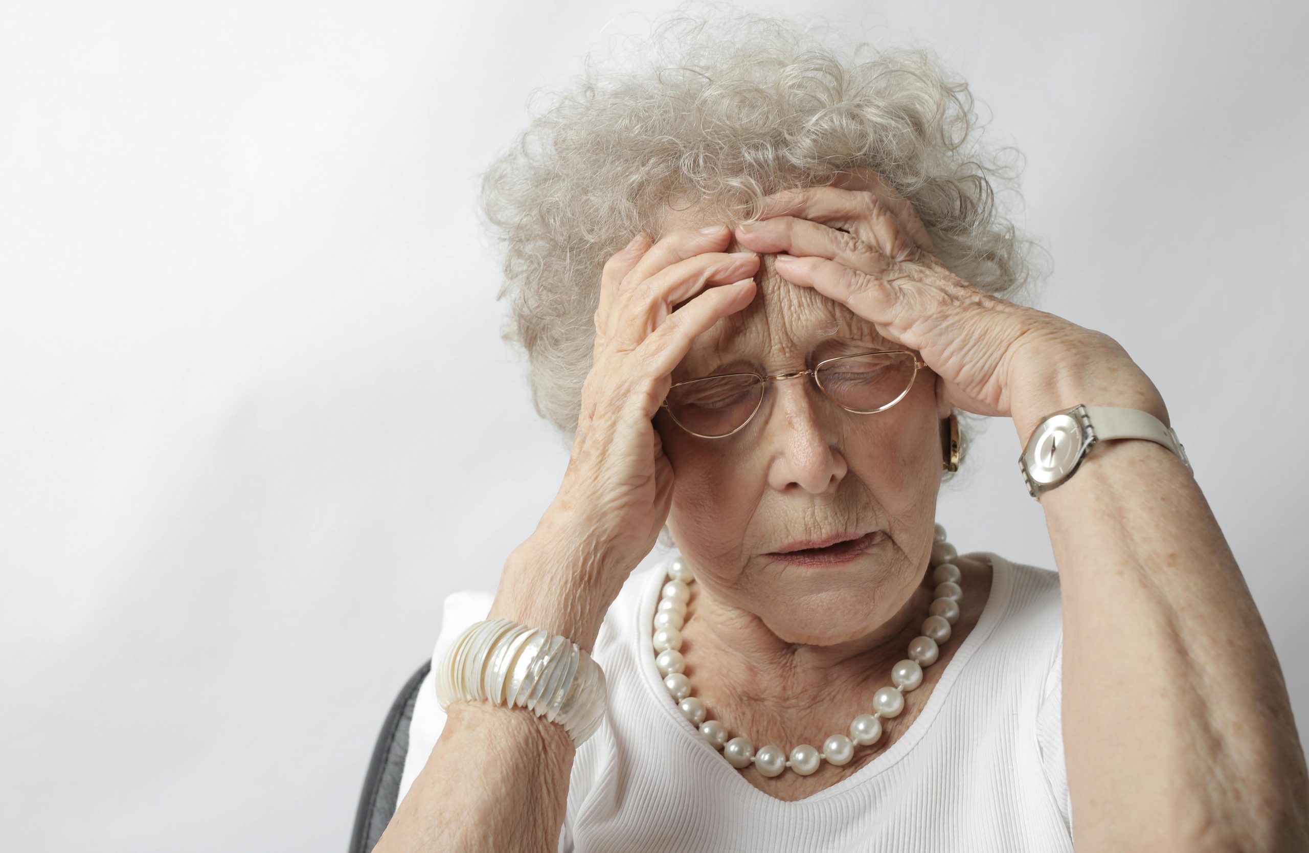 older woman in pain, with both hands on her head