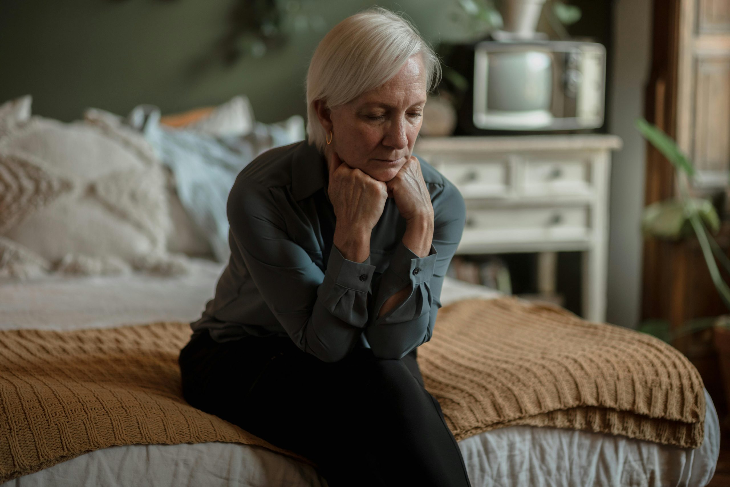 tired older woman sitting on a bed